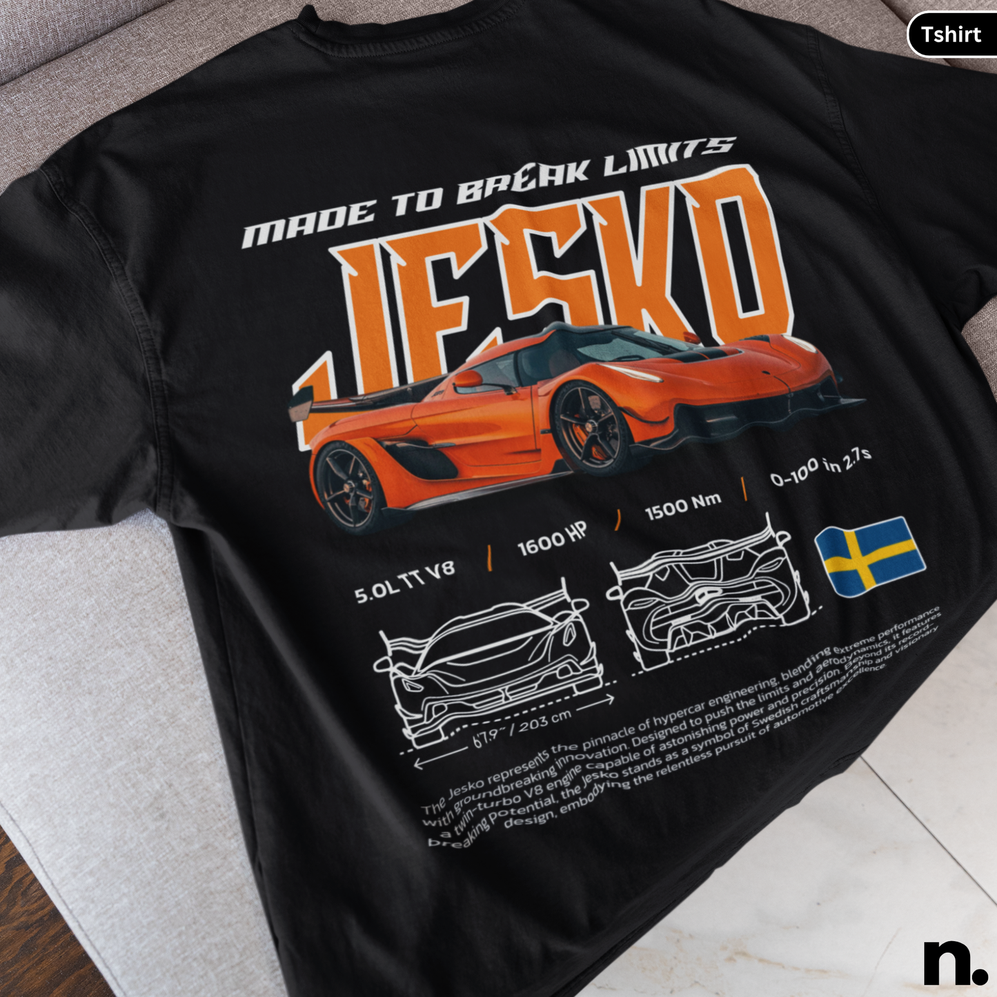 Black t-shirt with orange sports car design and text on a gray surface
