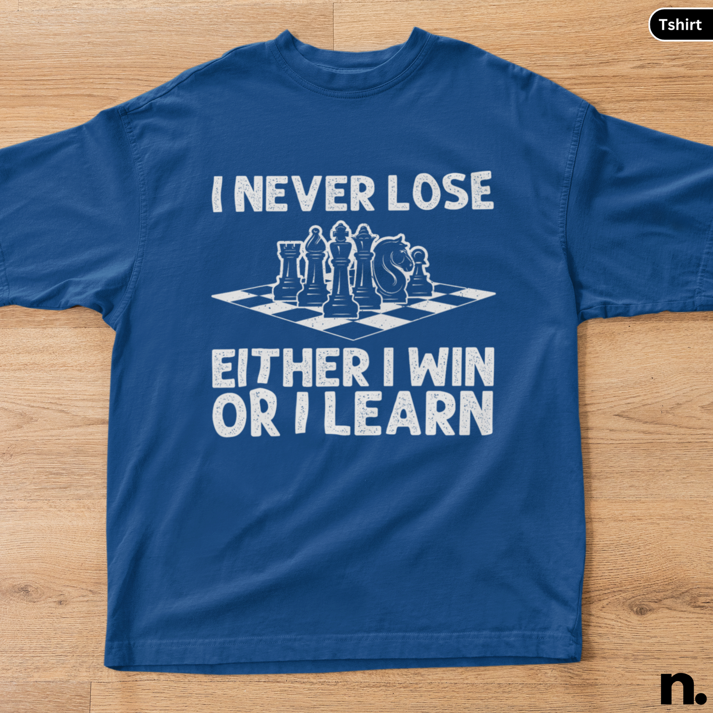 Blue t-shirt with chess design and text on a wooden surface