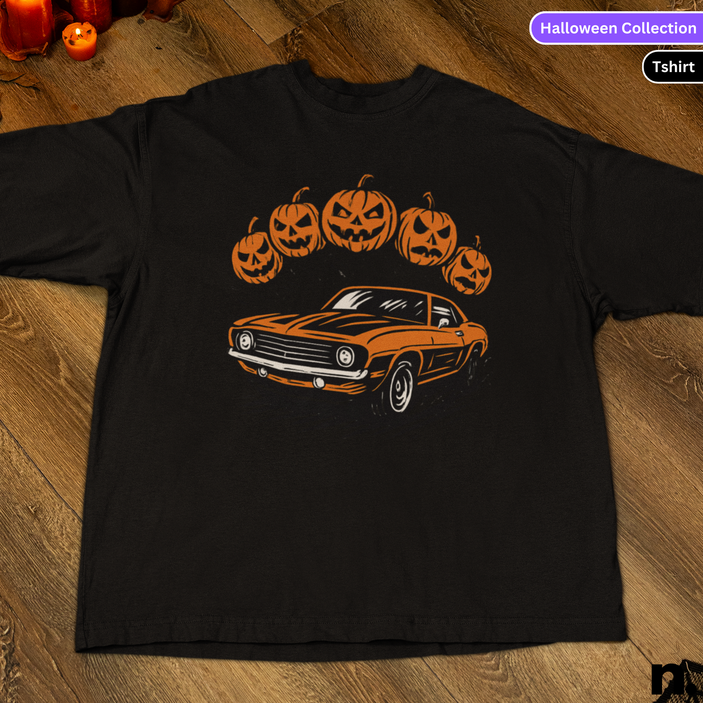 Black t-shirt with orange car and pumpkin design on a wooden surface, labeled 'Halloween Collection'.