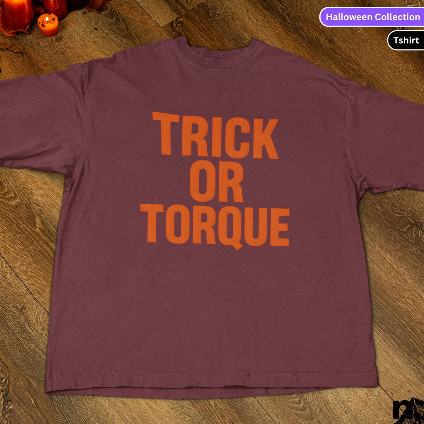 Purple t-shirt with 'TRICK OR TORQUE' text on a wooden surface, Halloween Collection label.