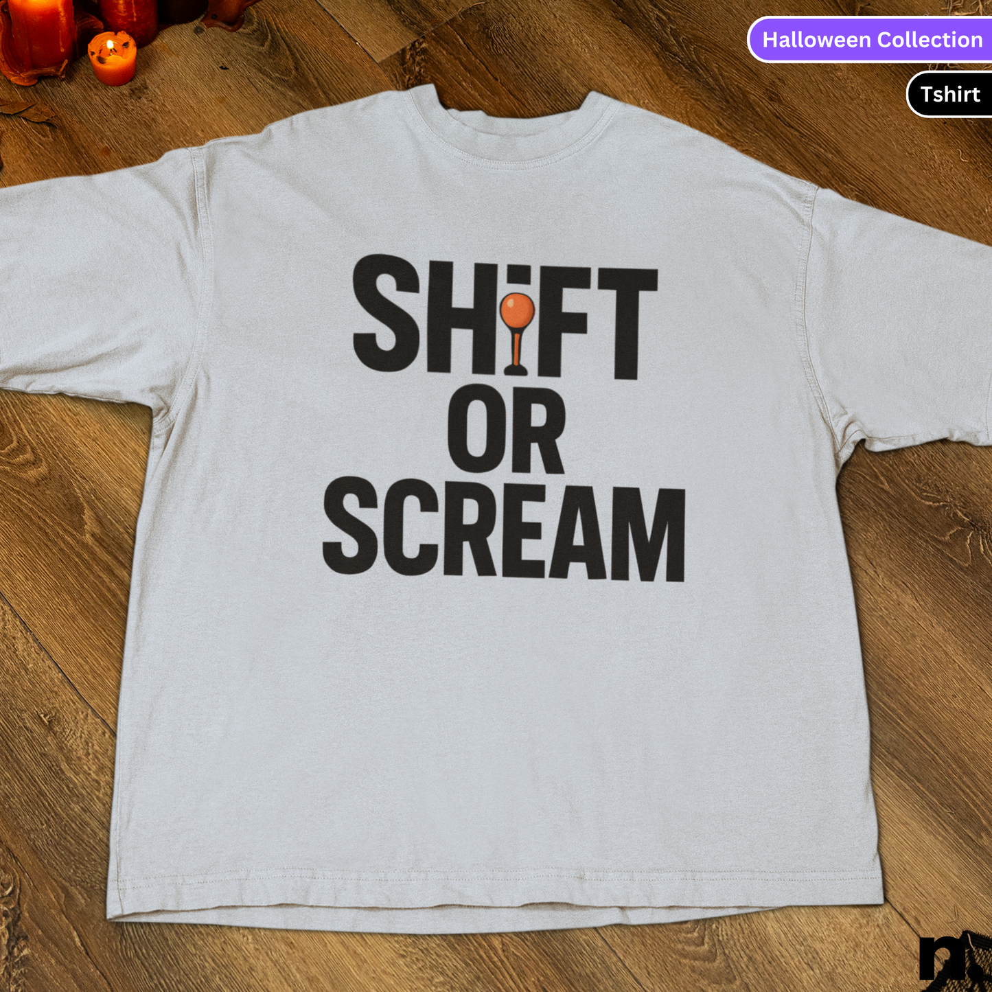 White t-shirt with 'SHIFT OR SCREAM' text on a wooden surface, labeled as part of a Halloween Collection.