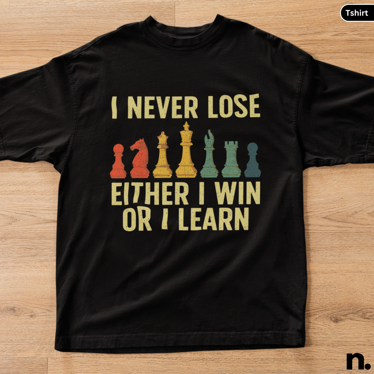 Black t-shirt with chess piece graphics and text on a wooden surface