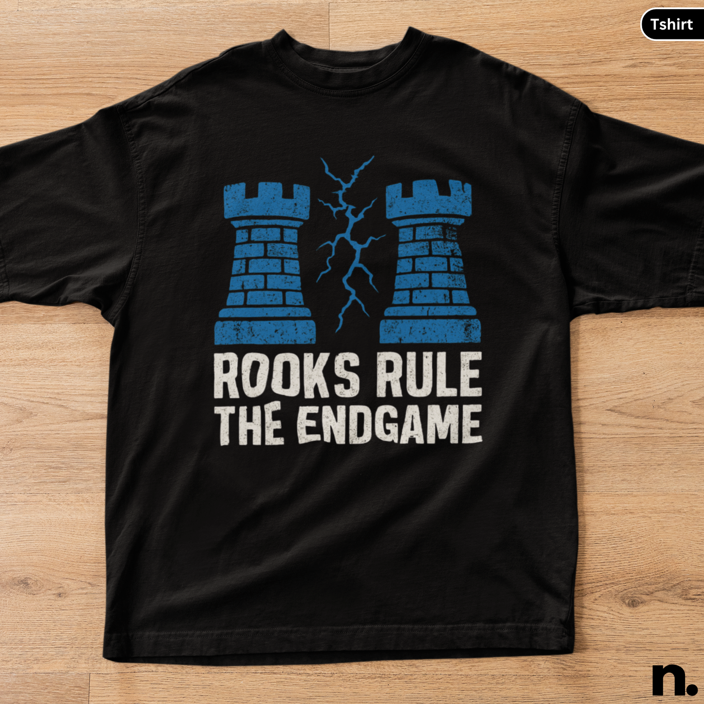 Black t-shirt with blue castle design and text 'Rooks Rule The Endgame' on a wooden surface.
