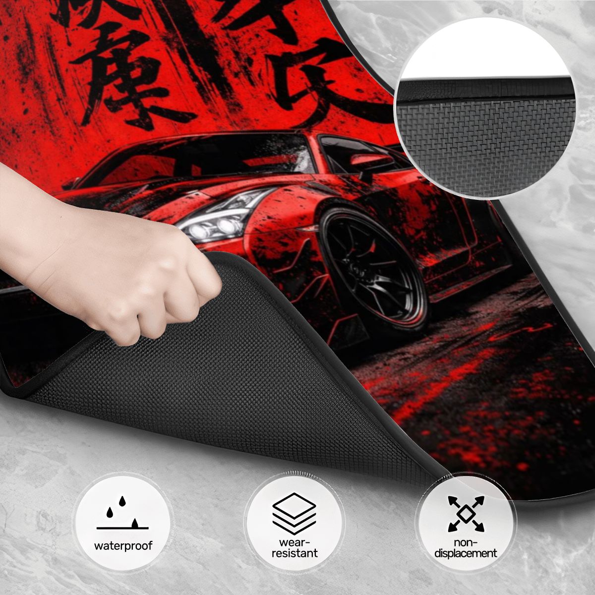 Car mat with red car design and text, held by a hand, on a gray surface.