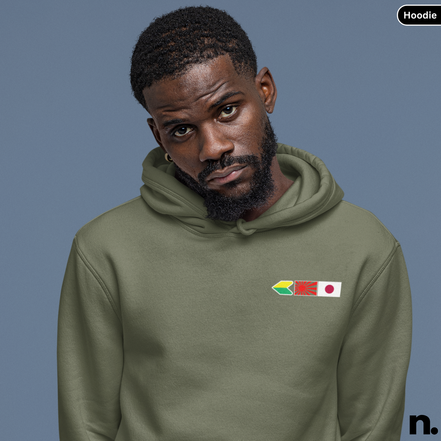 Man wearing a green hoodie with flag designs on a gray background