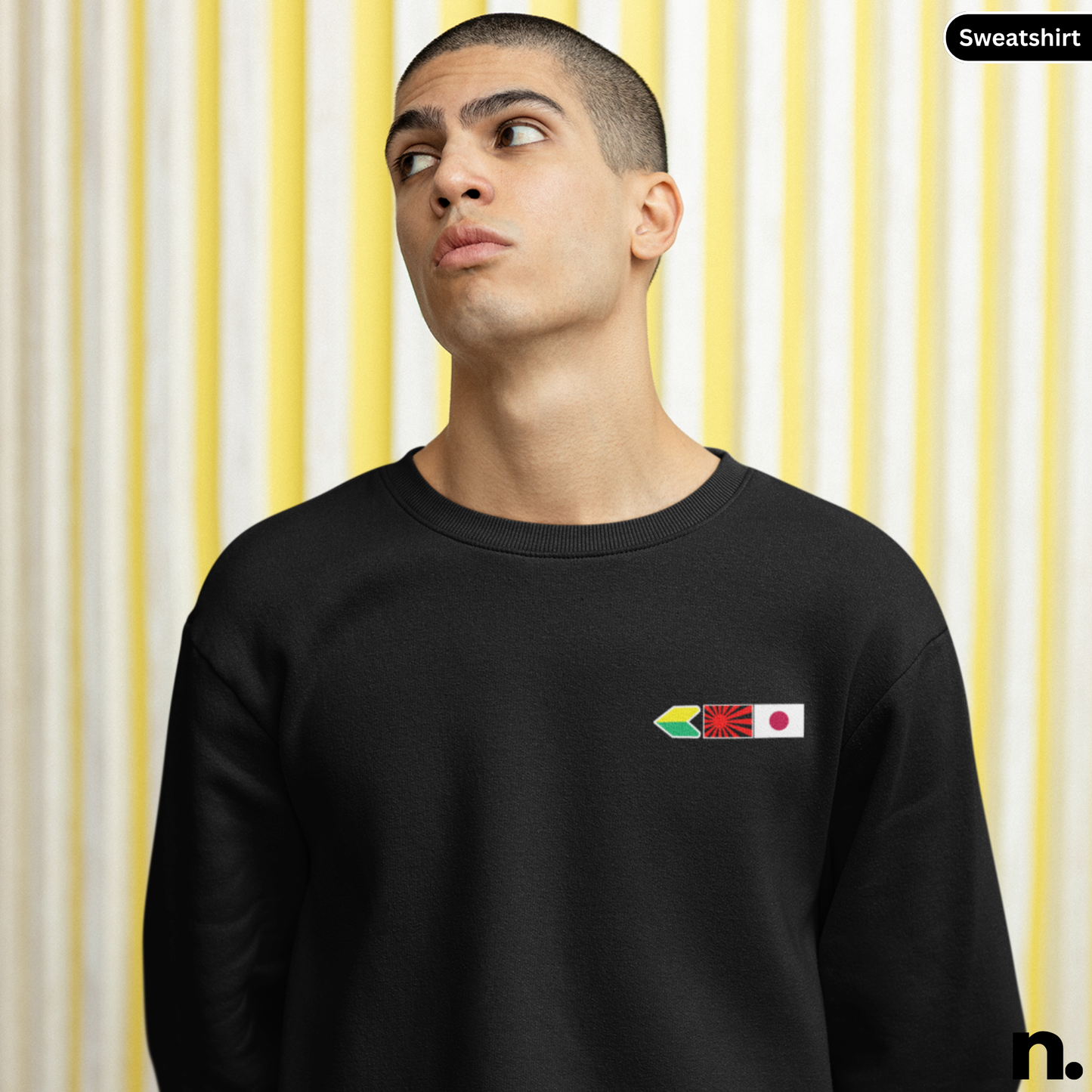 Person wearing a black sweatshirt with a colorful logo on a yellow and white striped background
