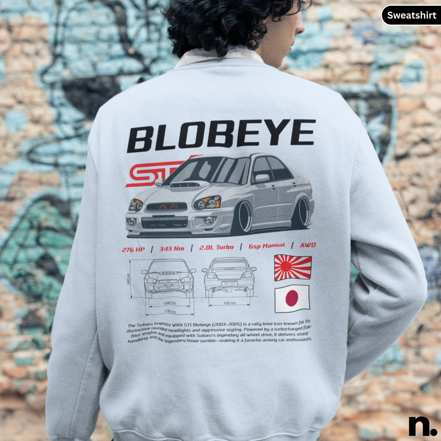 Person wearing a sweatshirt with 'Blobeye' design and car graphics on the back, against a graffiti-covered wall.