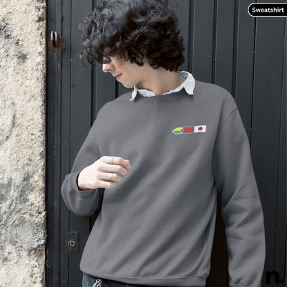 Person wearing a gray sweatshirt with a logo, standing against a dark door.