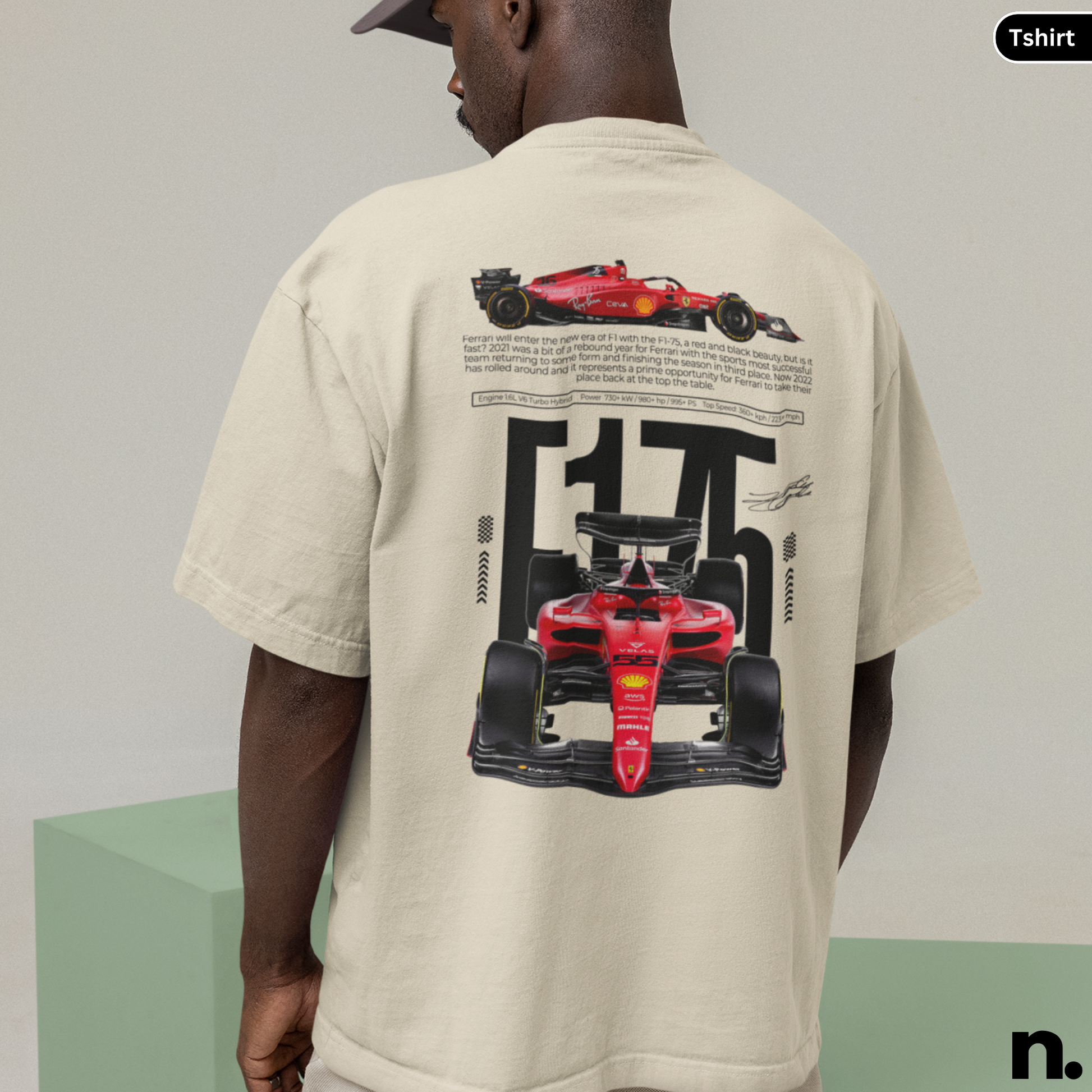 Person wearing a beige t-shirt with Formula 1 car graphics on the back, standing against a plain background.