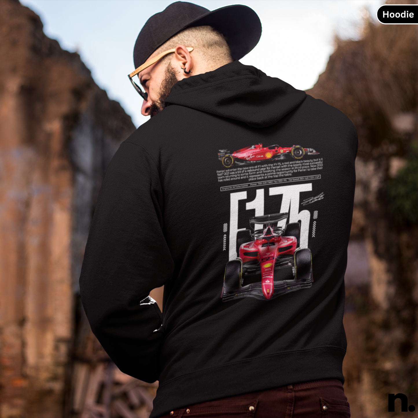 Person wearing a black hoodie with racing car design on the back, standing outdoors.