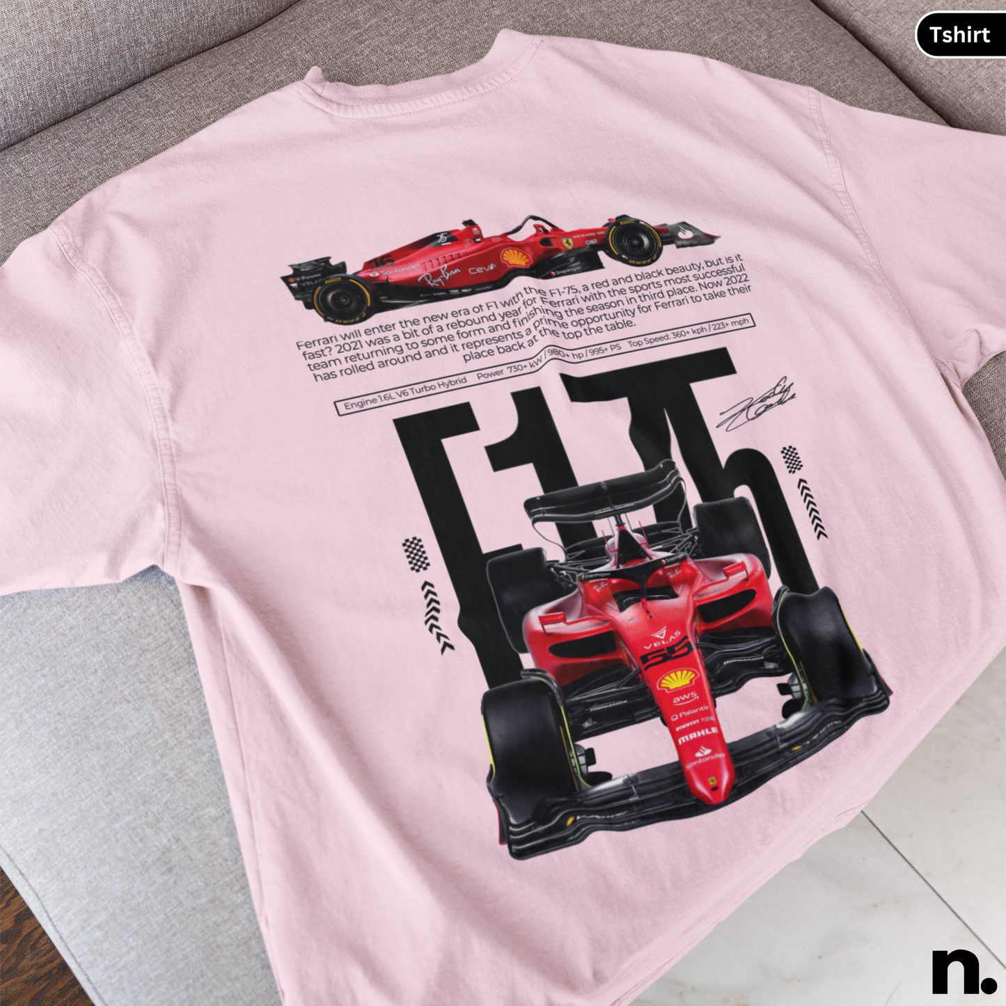 Pink t-shirt with Ferrari Formula 1 car design on a gray surface
