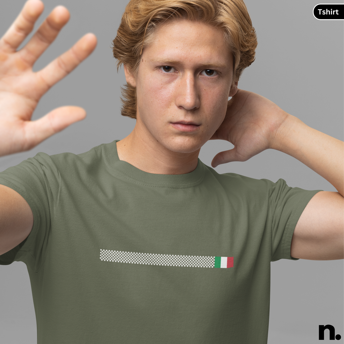 Man wearing a green t-shirt with a small flag design on a gray background