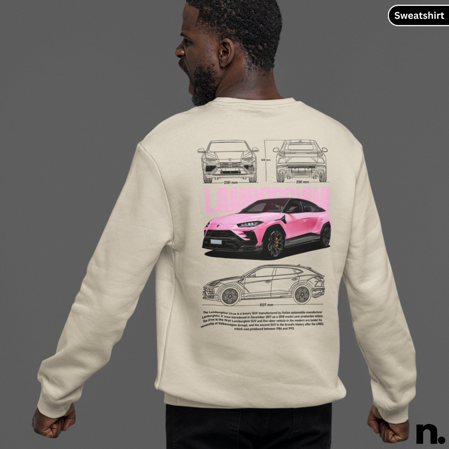Person wearing a beige sweatshirt with car design on the back, on a gray background