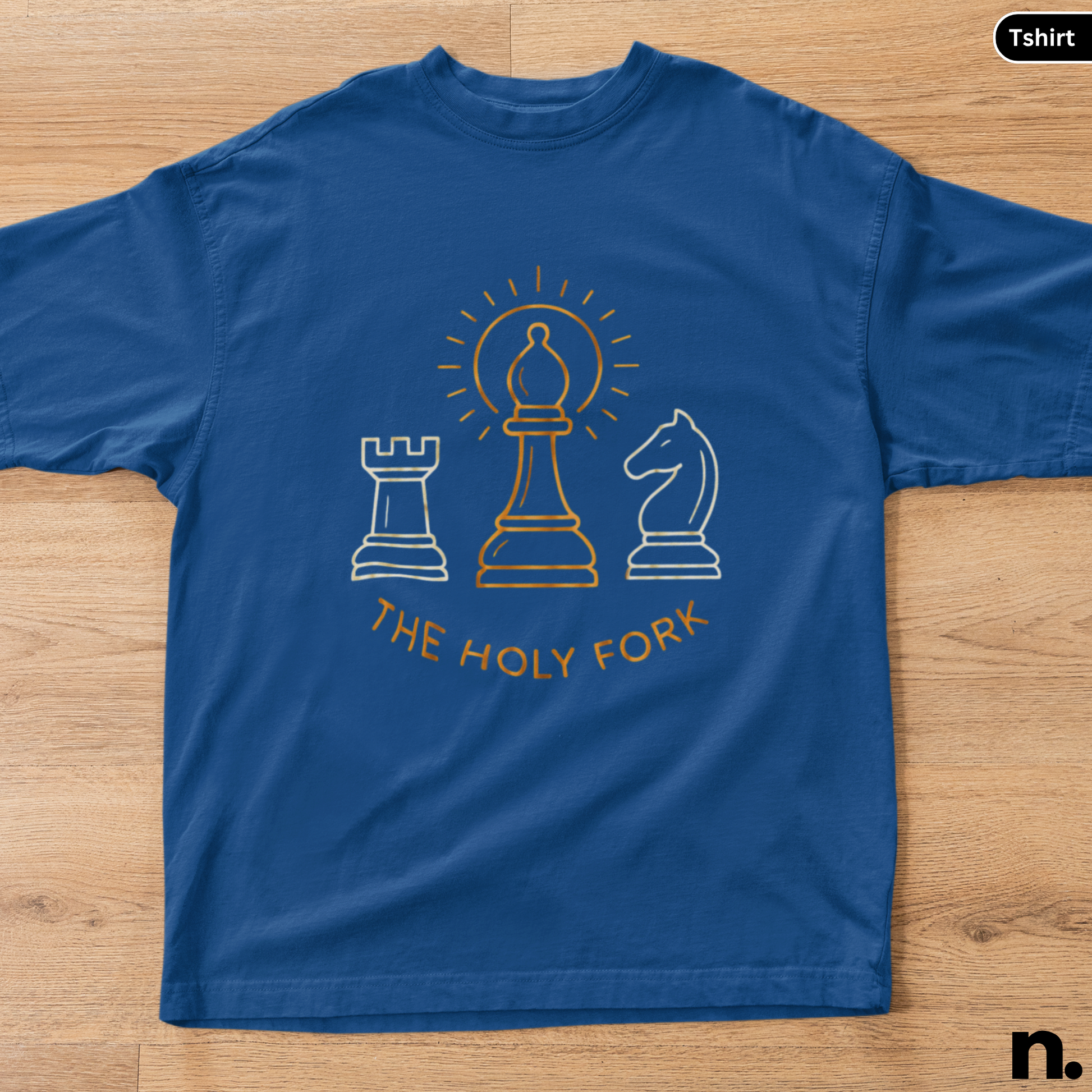 Blue t-shirt with chess piece graphics and 'The Holy Fork' text on a wooden surface