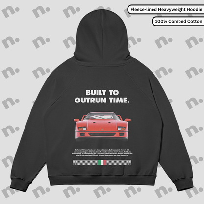 Flat lay of a premium black hoodie featuring a stylized Ferrari F40 graphic and the phrase "Built to Outrun Time", displayed with streetwear elements on a minimalist background.
