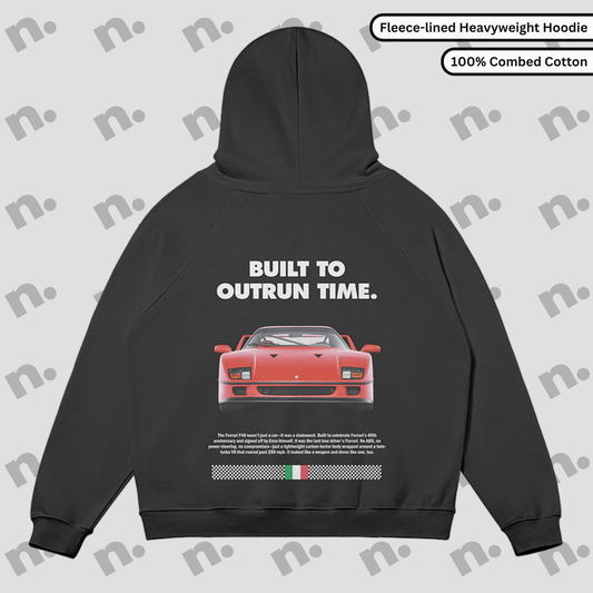 Flat lay of a premium black hoodie featuring a stylized Ferrari F40 graphic and the phrase "Built to Outrun Time", displayed with streetwear elements on a minimalist background.
