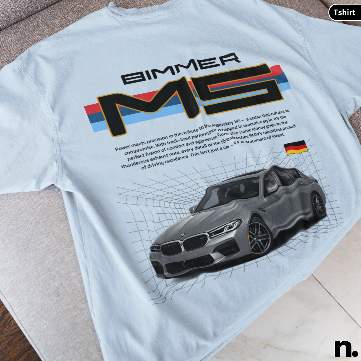 White t-shirt with BMW M5 graphic and text on a wooden surface