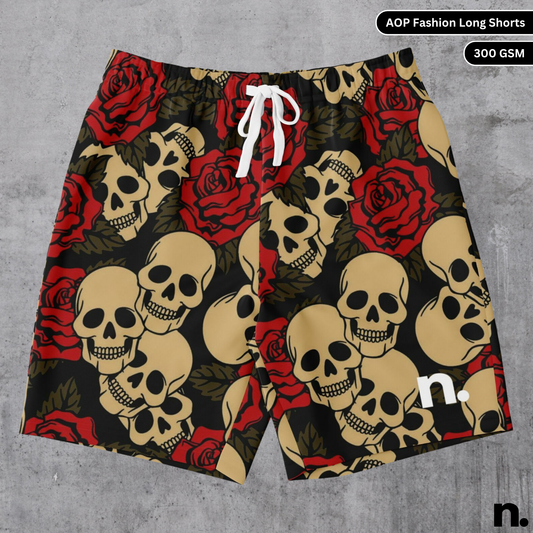 A flat lay of men's long shorts with an all-over print featuring a detailed pattern of skulls intertwined with roses, and a brand logo visible on the design, showcasing the drawstring closure and pockets.