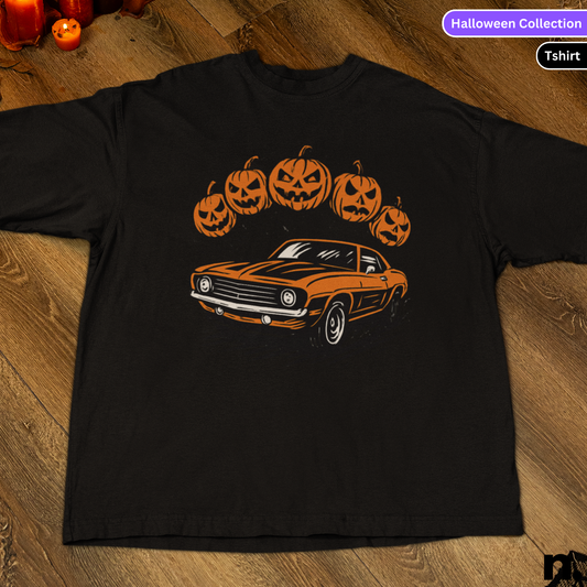Black t-shirt with orange car and pumpkin design on a wooden surface, labeled 'Halloween Collection'.