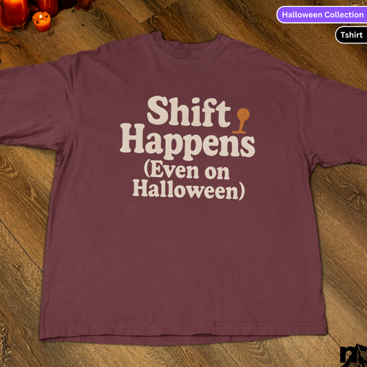 Maroon t-shirt with 'Shift Happens (Even on Halloween)' text on a wooden surface.