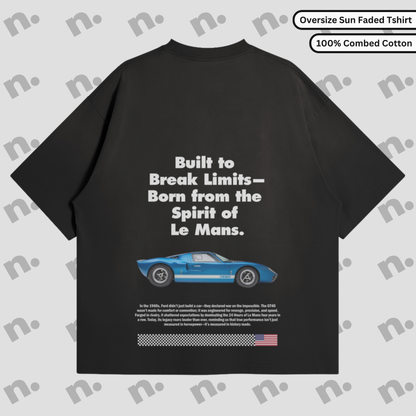 Flat lay of a premium T-shirt featuring a bold GT40 Le Mans poster-style graphic, arranged with vintage racing accessories on a clean background.