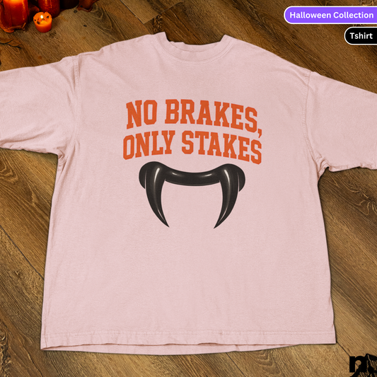 Pink t-shirt with 'No Brakes, Only Stakes' text and black graphic on a wooden surface.