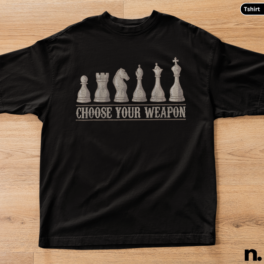 Black t-shirt with chess piece design and 'Choose Your Weapon' text on a wooden surface