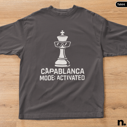 Gray t-shirt with a chess piece graphic and text on a wooden surface
