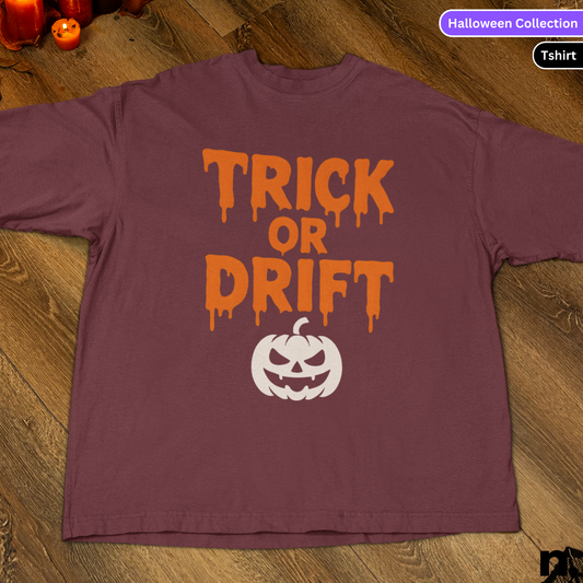 Purple t-shirt with 'Trick or Drift' text and pumpkin graphic on a wooden surface