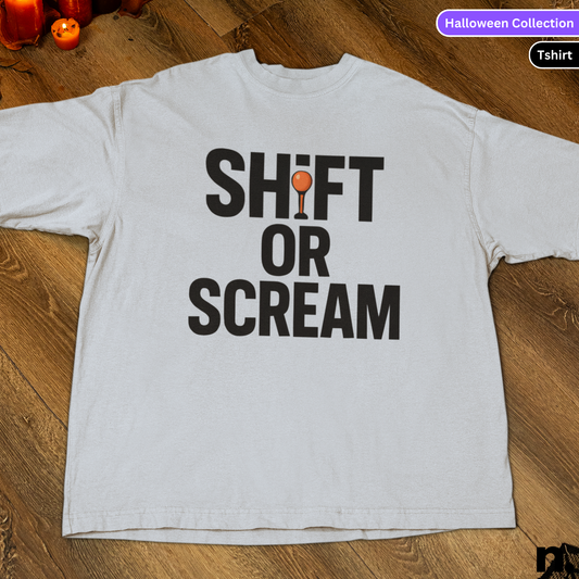 White t-shirt with 'SHIFT OR SCREAM' text on a wooden surface, labeled as part of a Halloween Collection.