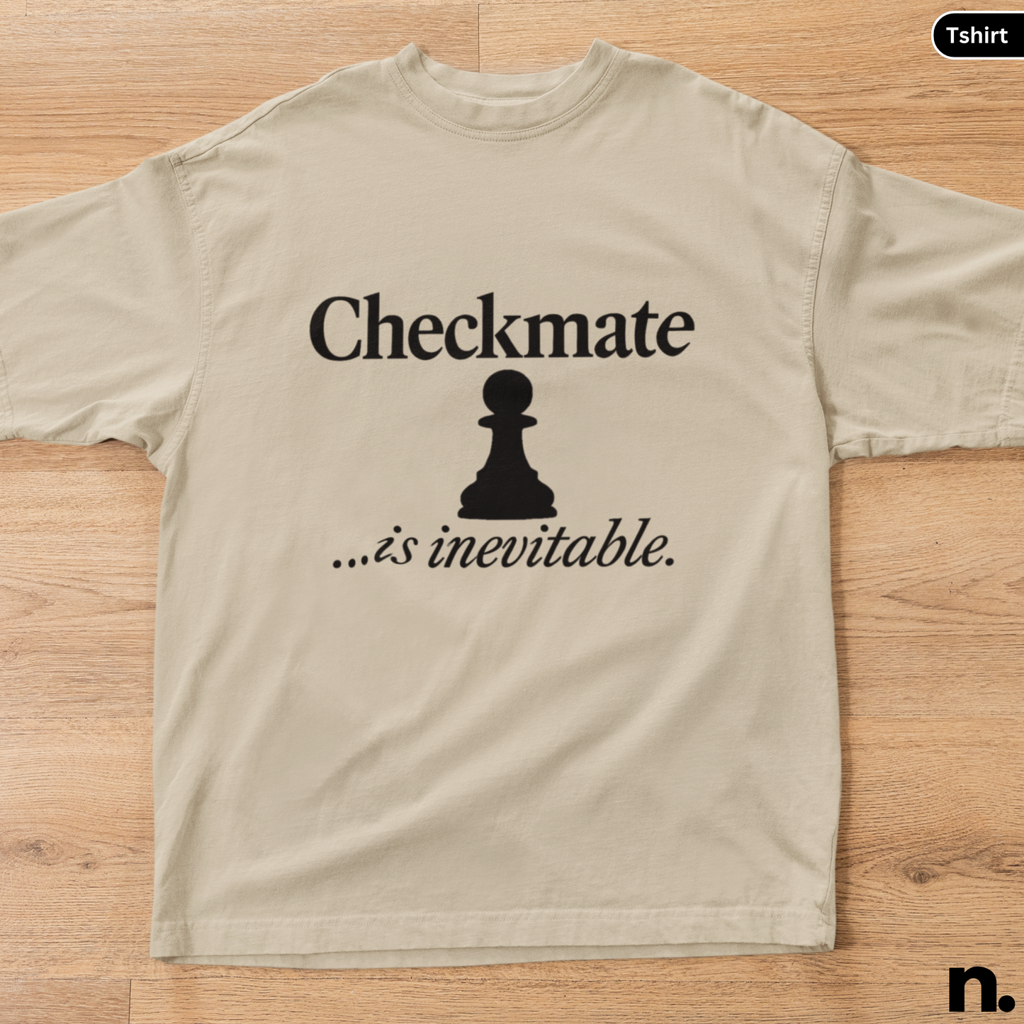Beige t-shirt with a black chess piece and text on a wooden surface
