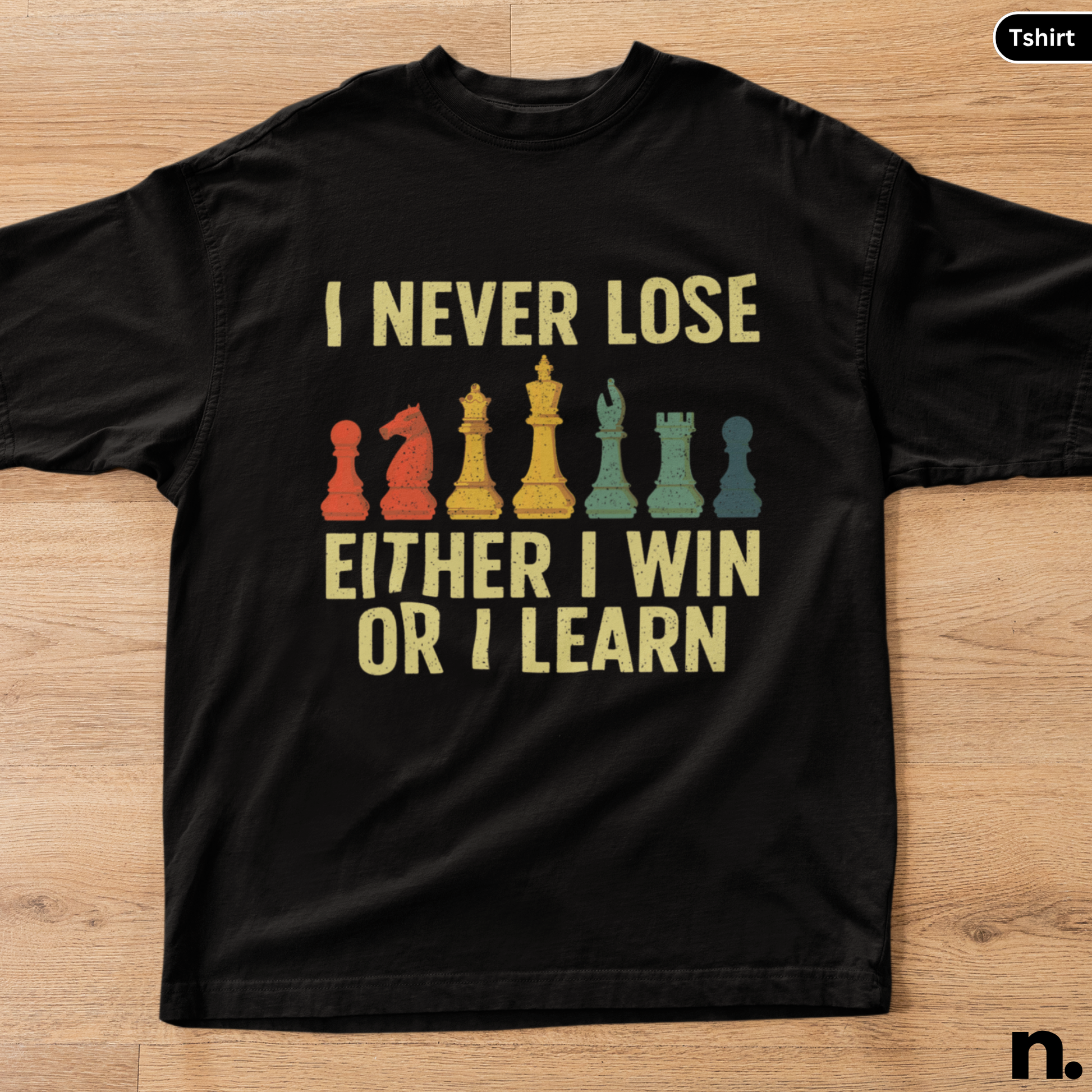 Black t-shirt with chess piece graphics and text on a wooden surface
