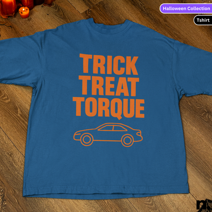 Blue t-shirt with 'Trick Treat Torque' text and car graphic on a wooden surface.