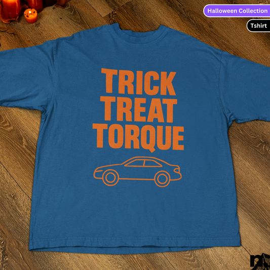 Blue t-shirt with 'Trick Treat Torque' text and car graphic on a wooden surface.