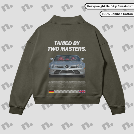 Flat lay of half-zip fleece-lined sweatshirt with bold automotive-inspired “TAMED BY TWO MASTERS.” graphic, drop shoulders, and stand collar in an oversized fit.

