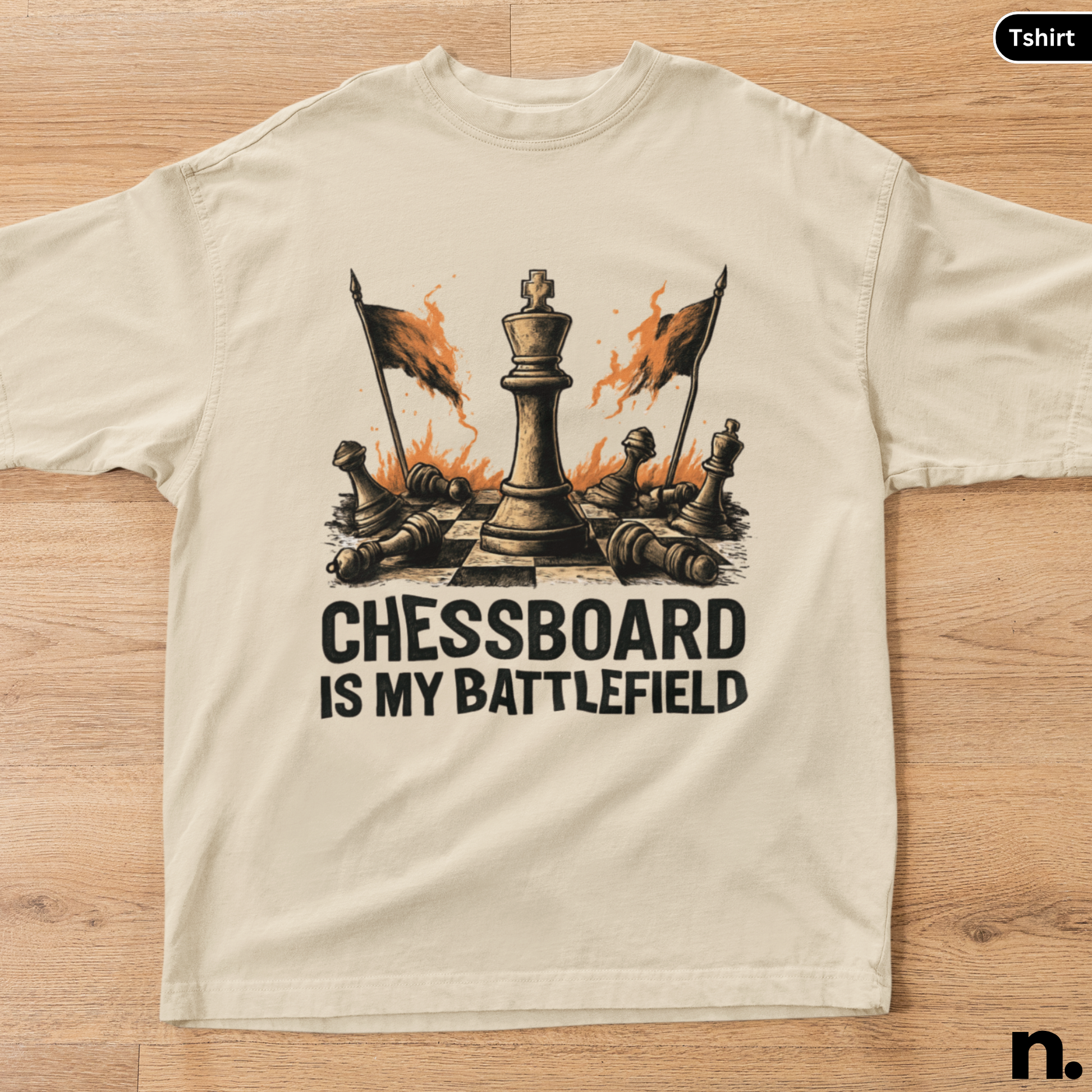 Beige t-shirt with a chess-themed graphic and text 'Chessboard is my battlefield' on a wooden surface.