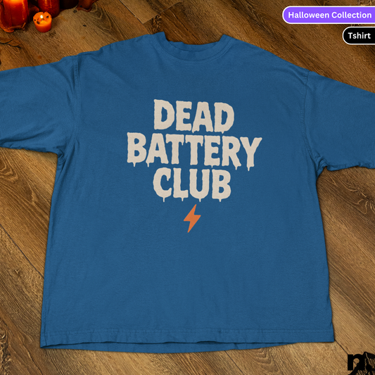 Blue t-shirt with 'DEAD BATTERY CLUB' text on a wooden floor