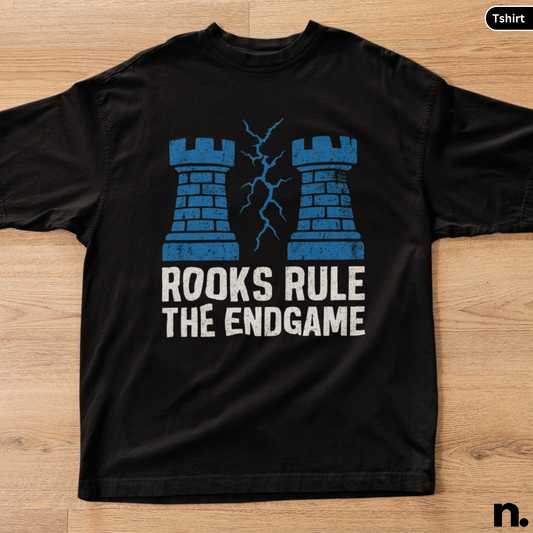 Black t-shirt with blue castle design and text 'Rooks Rule The Endgame' on a wooden surface.