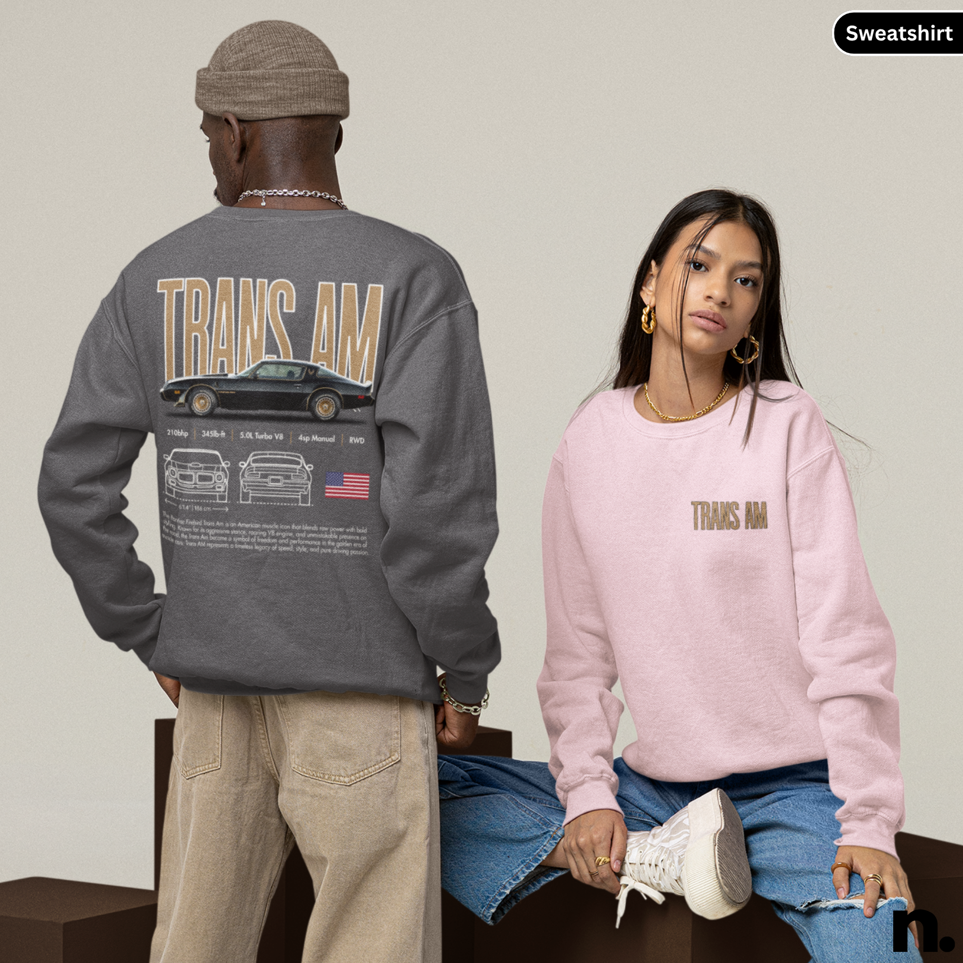 Two people wearing sweatshirts with 'TRANS AM' text and graphics on a neutral background.