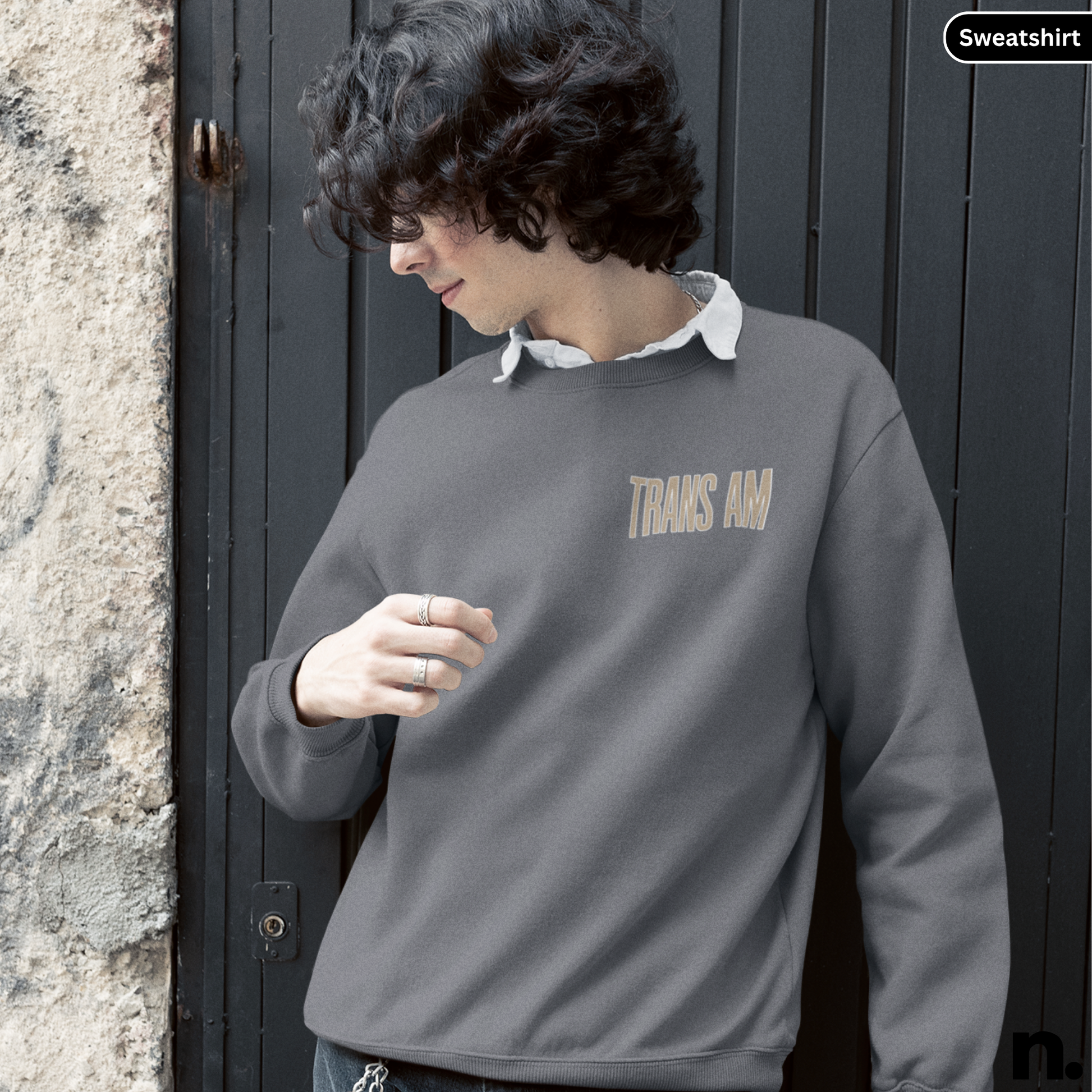 Person wearing a gray sweatshirt with 'THANK YOU' text, standing against a dark door.
