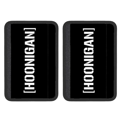Two black neoprene seat belt cover pads with the white text 'HOONIGAN' on them, displayed against a white background.